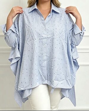 Femme portant une blouse ample bleu ciel à pois, grande taille, avec pantalon blanc